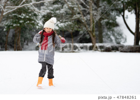 雪の降った公園で遊ぶ女の子の写真素材