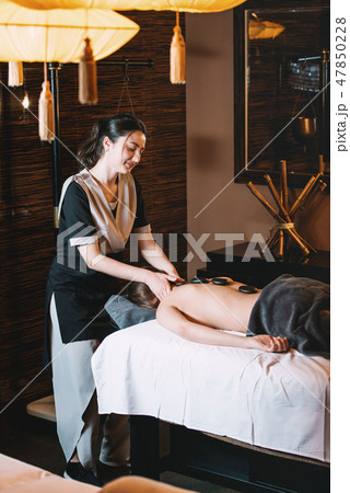 Specialist making hot stone massage to a client Specialist making hot stone massage to a client 47850228
