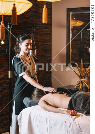Specialist making hot stone massage to a client. 47850231