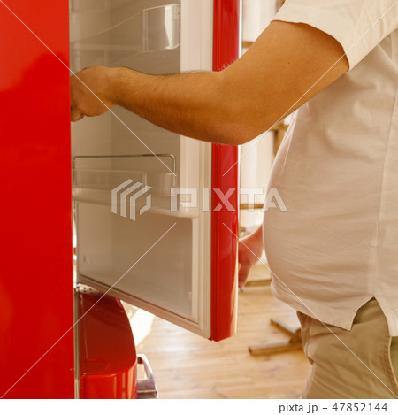 obese man plunging into fridge looking for snack 47852144