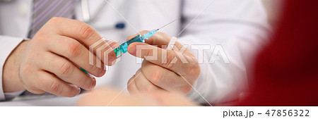 Physician injector arms in sterile uniform holding syringe Physician injector arms in sterile uniform holding syringe 47856322