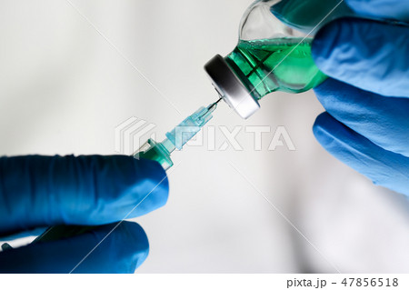 Physician injector arms in sterile uniform holding syringe 47856518