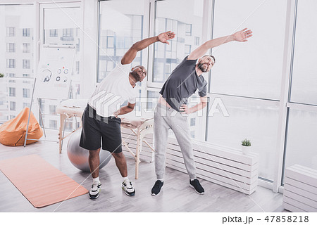 Positive delighted males doing training in gym 47858218
