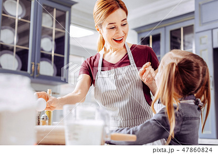 Happy woman smiling and pointing to the cookie of her little daughter Happy woman smiling and pointing to the cookie of her little daughter 47860824