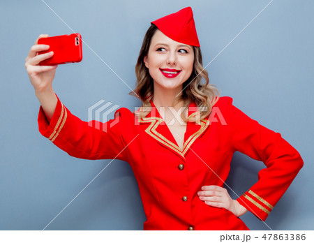 stewardess wearing in red uniform with mobile phone stewardess wearing in red uniform with mobile phone 47863386