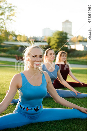 a group of adult women attending yoga outside in the park 47864969