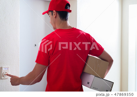 Courier man carrying cardboard boxes ringing the doorbell Courier man carrying cardboard boxes ringing the doorbell 47869350
