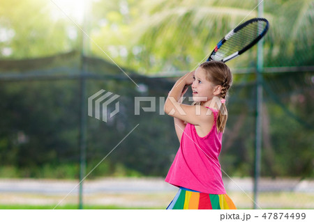 Child playing tennis on outdoor court 47874499