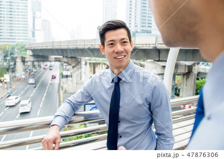 Asian businessman talking with colleague outdoors Asian businessman talking with colleague outdoors 47876306