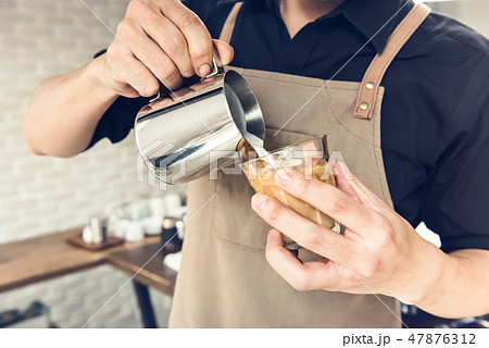 Barista pouring steamed milk into coffee cup Barista pouring steamed milk into coffee cup 47876312