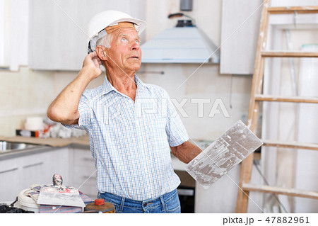 Foreman with plastering tools looking at repairable room 47882961