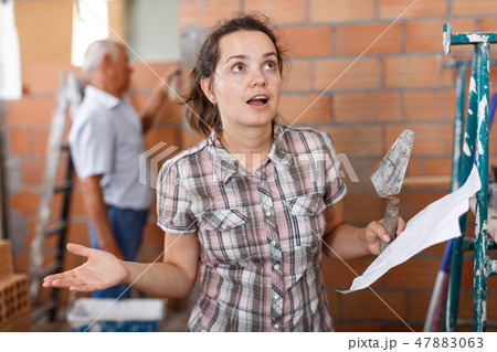 Surprised woman with paper during renovation 47883063