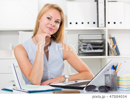 portrait of woman sitting at workplace and smiling in office portrait of woman sitting at workplace and smiling in office 47884034