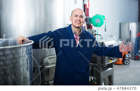 positive mature man working in wine secondary fermentation section 47884370