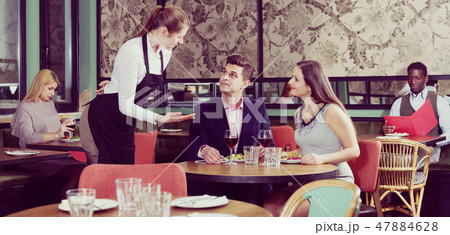 Couple talking with waitress in restaurant Couple talking with waitress in restaurant 47884628