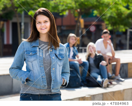 Portrait of teenager girl standing aside from friends outdoors Portrait of teenager girl standing aside from friends outdoors 47884963
