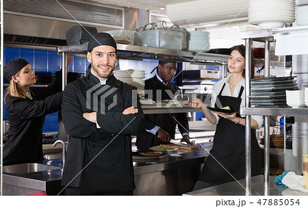Smiling chef cook is posing on kitchen in restaurant. Smiling chef cook is posing on kitchen in restaurant. 47885054