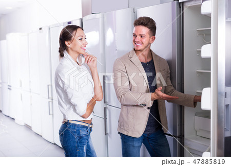 young glad couple choosing new refrigerator in hypermarket young glad couple choosing new refrigerator in hypermarket 47885819