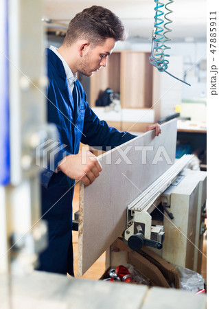 Positive guy fixing chipboard on table at workshop 47885911