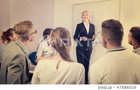Female teacher lecturing to students at auditorium Female teacher lecturing to students at auditorium 47886026