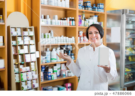 Glad mature female seller with box in pharmaceutical store 47886066