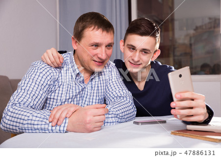 Man with his adult son are taking selfie together Man with his adult son are taking selfie together 47886131
