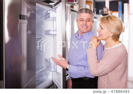 Charming mature married couple choose for themselves refrigerator Charming mature married couple choose for themselves refrigerator 47886485