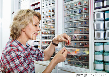Mature glad woman customer picking various buttons Mature glad woman customer picking various buttons 47886757