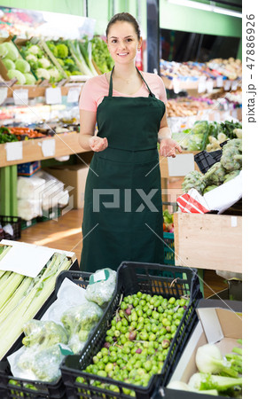 Friendly salesgirl proposing fresh fruits and vegetables in supermarket 47886926