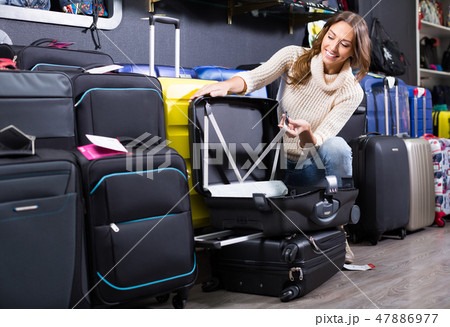 Young female purchasing travel suitcase 47886977