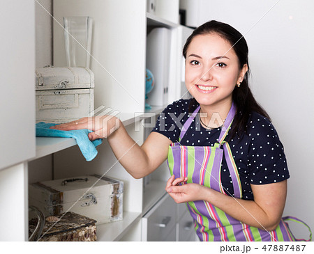 Smiling girl wiping dust on shelves 47887487