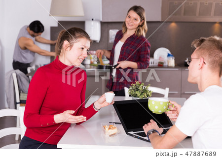 Female helping guy to plan tourist itinerary at hostel kitchen Female helping guy to plan tourist itinerary at hostel kitchen 47887689