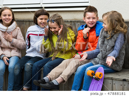 Kids whispering in other ears outdoor. Kids whispering in other ears outdoor. 47888181