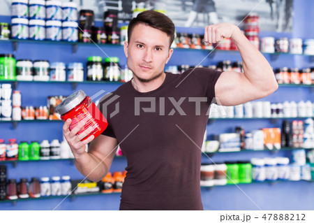 Young sporty man standing with sport nutrition in store 47888212
