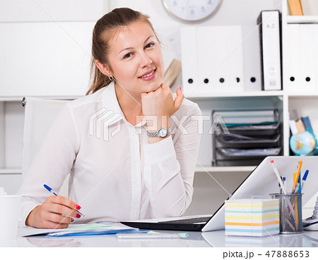 Young woman is posing while working behind laptop Young woman is posing while working behind laptop 47888653