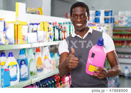 satisfied African man holding bottle of household chemicals in store satisfied African man holding bottle of household chemicals in store 47888900