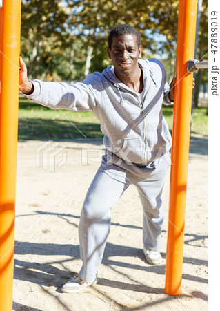 Young male training different exercises at chin-up bar in park outdoor Young male training different exercises at chin-up bar in park outdoor 47889019