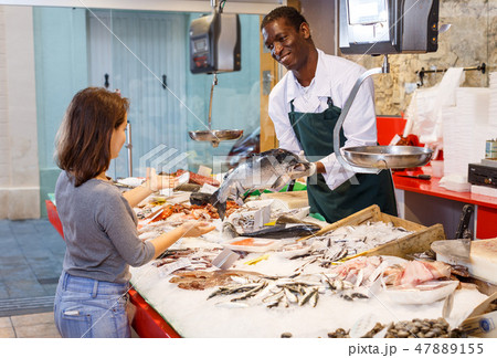 Salesman serving customer raw fish Salesman serving customer raw fish 47889155