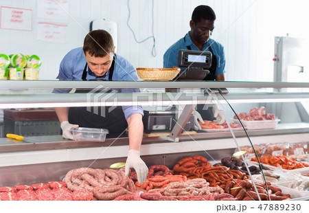 Successful owner of butcher store with his worker preparing fresh meat products for sale Successful owner of butcher store with his worker preparing fresh meat products for sale 47889230