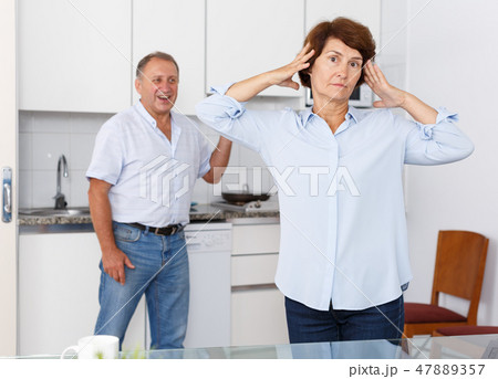 Upset mature woman standing after qurrel with husband at home 47889357