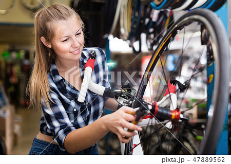 Young woman master is repairing wheel of bicycle Young woman master is repairing wheel of bicycle 47889562