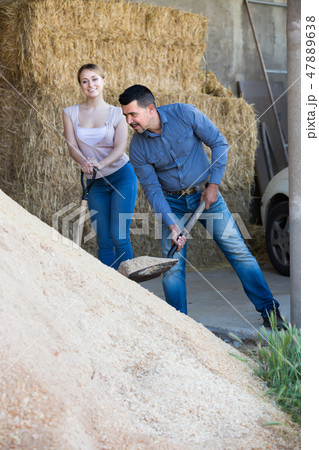 Two smiling farm workers holding big shovels 47889638