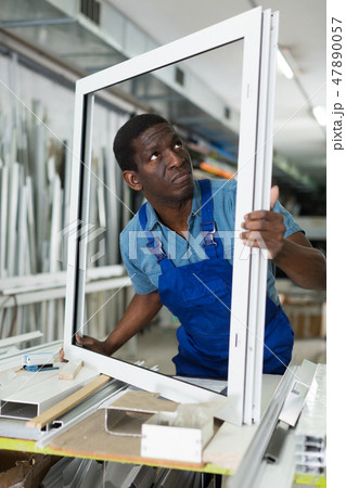 Male master is working with window frame 47890057