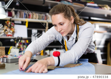 Smiling woman tailor working with marker for modeling clothes Smiling woman tailor working with marker for modeling clothes 47890338