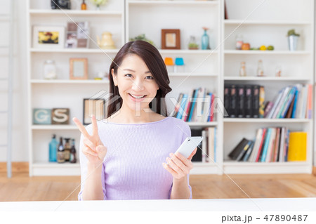 部屋でスマホを見る女性 部屋でスマホを見る女性 47890487