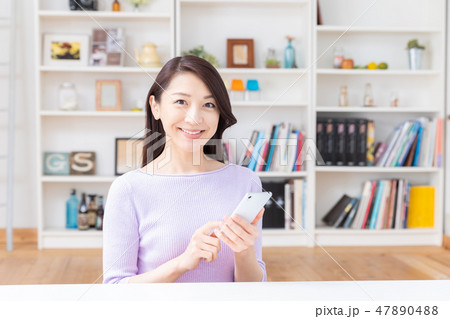 部屋でスマホを見る女性 47890488