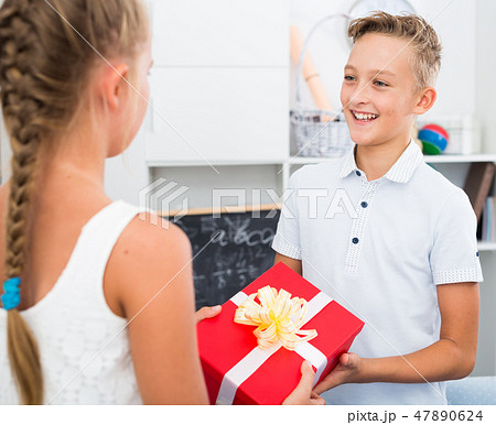 Girl is giveing a gift to friend on his birthday 47890624