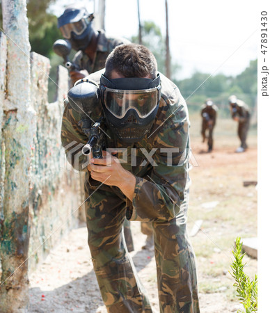 Male paintball player aiming with gun Male paintball player aiming with gun 47891430