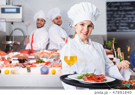 Attractive female chef with serving tray, offering dishes in fish restaurant Attractive female chef with serving tray, offering dishes in fish restaurant 47891840