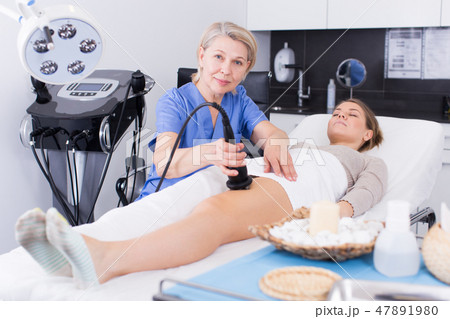 Cosmetologist with client during hardware procedure 47891980